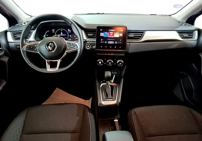 Vue intérieure avant du Renault Captur bleu, tableau de bord moderne avec écran tactile central et volant multifonctions.