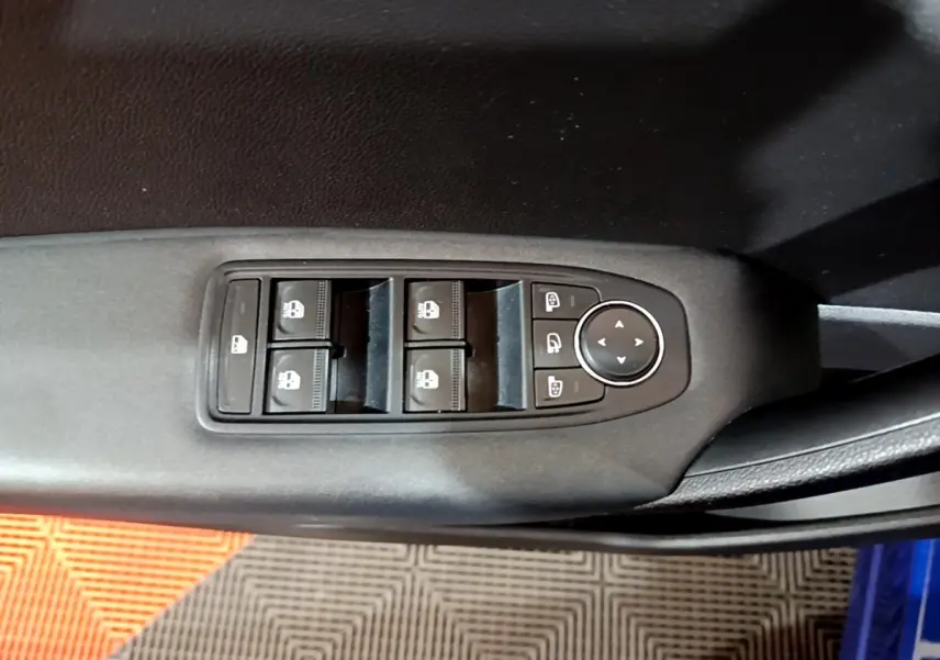 Vue rapprochée des commandes de lève-vitres et réglages des rétroviseurs sur la porte côté conducteur d’un Renault Captur bleu.