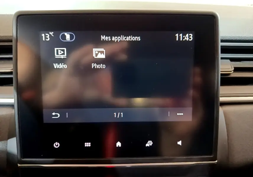 Écran tactile central du tableau de bord du Renault Captur bleu, affichant les applications vidéo et photo.