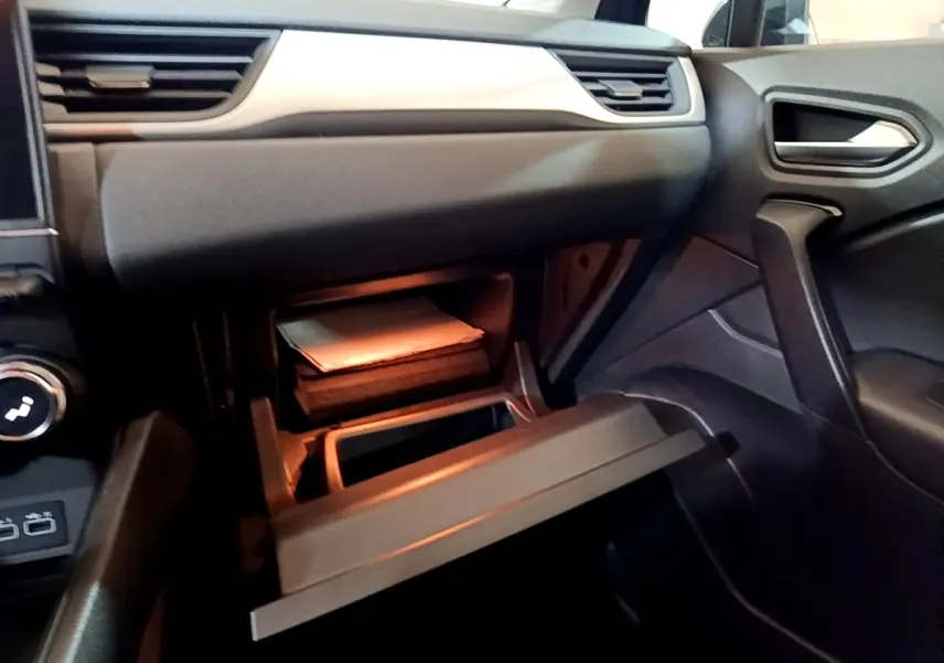 Intérieur Renault Captur 2023, vue côté passager sur boîte à gants ouverte avec éclairage intérieur chaud.