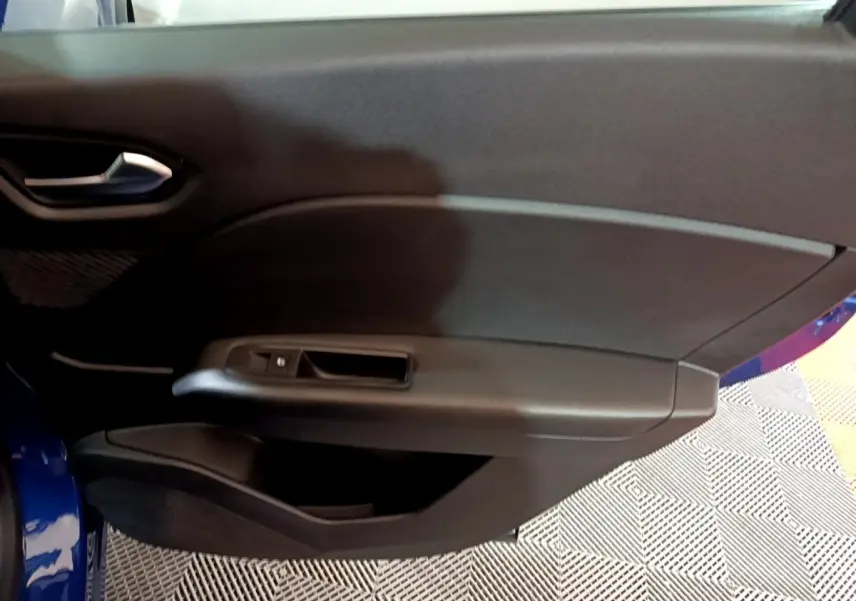 Vue intérieure du panneau de porte avant gauche du Renault Captur bleu, avec commande de fenêtre et poignée intégrée.