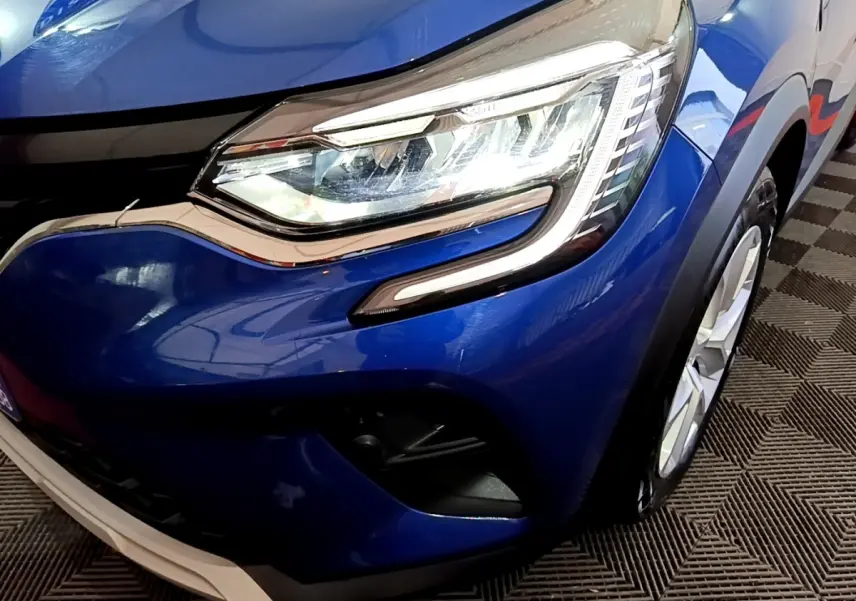 Gros plan sur l'avant droit bleu du Renault Captur 2023 avec phare LED et partie de la roue visible.