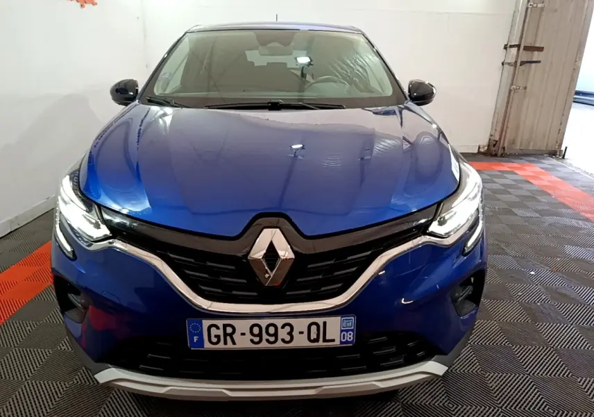 Vue avant d'un Renault Captur bleu 2023 avec phares LED allumés et calandre noire chromée.