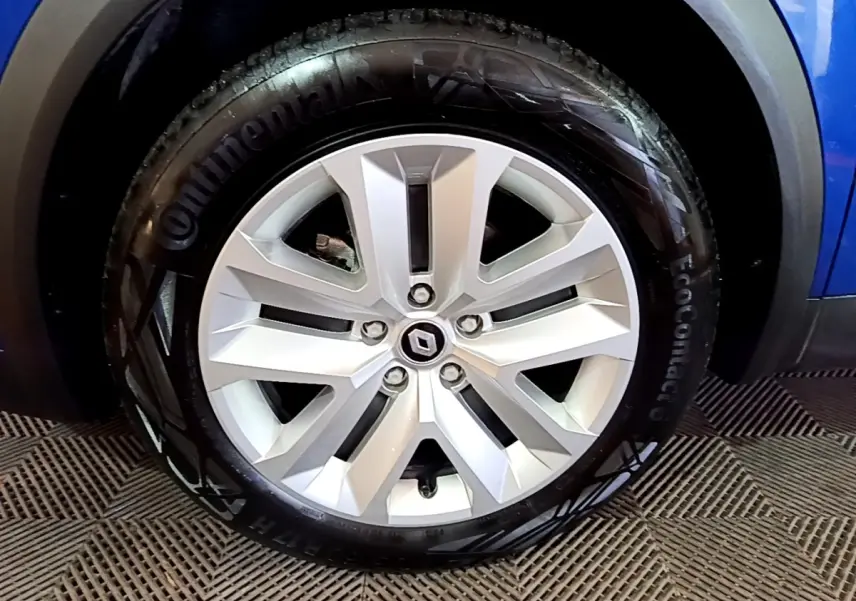 Vue rapprochée de la roue arrière droite d’un Renault Captur bleu 2023 avec jante alliage et passage de roue noir.