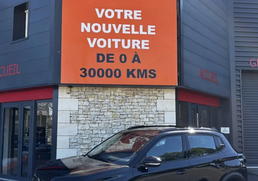 Citroën C3 noire vue en 3/4 avant droit, avec jantes 16 pouces et toit avec rails noirs devant un bâtiment commercial.
