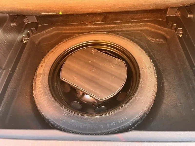 Vue du coffre ouvert d'une Citroën C5 Aircross gris, montrant la roue de secours et son compartiment.