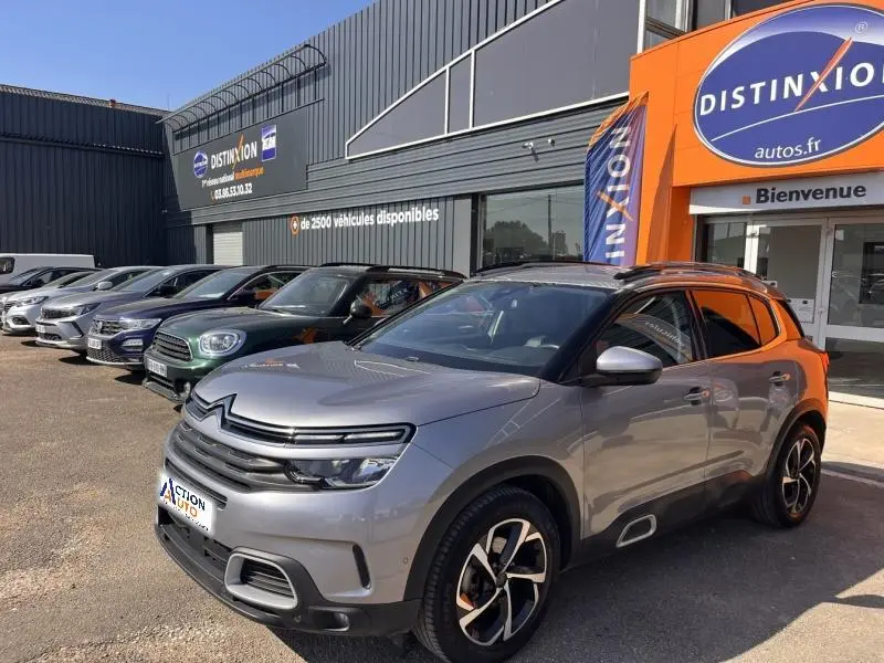 Vue 3/4 avant droite d'un Citroën C5 Aircross gris métallisé avec jantes alliage et toit noir, devant un concessionnaire.