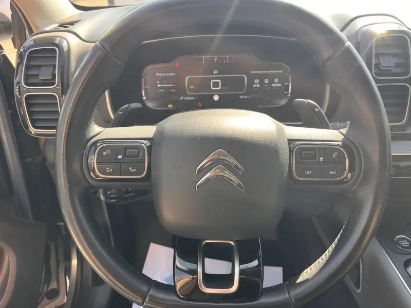 Vue centrée sur le volant cuir multifonction noir du Citroën C5 Aircross avec tableau de bord numérique en arrière-plan.