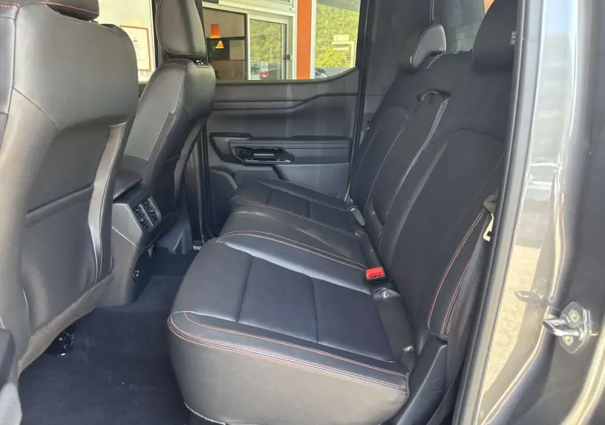 Vue intérieure côté droit des sièges arrière en cuir noir avec surpiqûres orange du Ford Ranger Wildtrak Plus gris carbone 2026.
