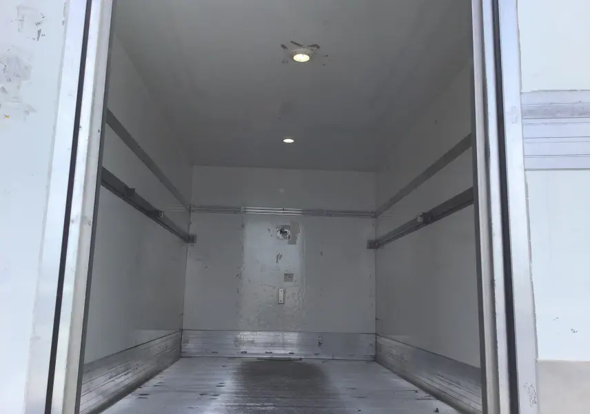 Vue intérieure de la caisse aluminium du Volkswagen Crafter bleu, montrant le plancher et l’éclairage au plafond.