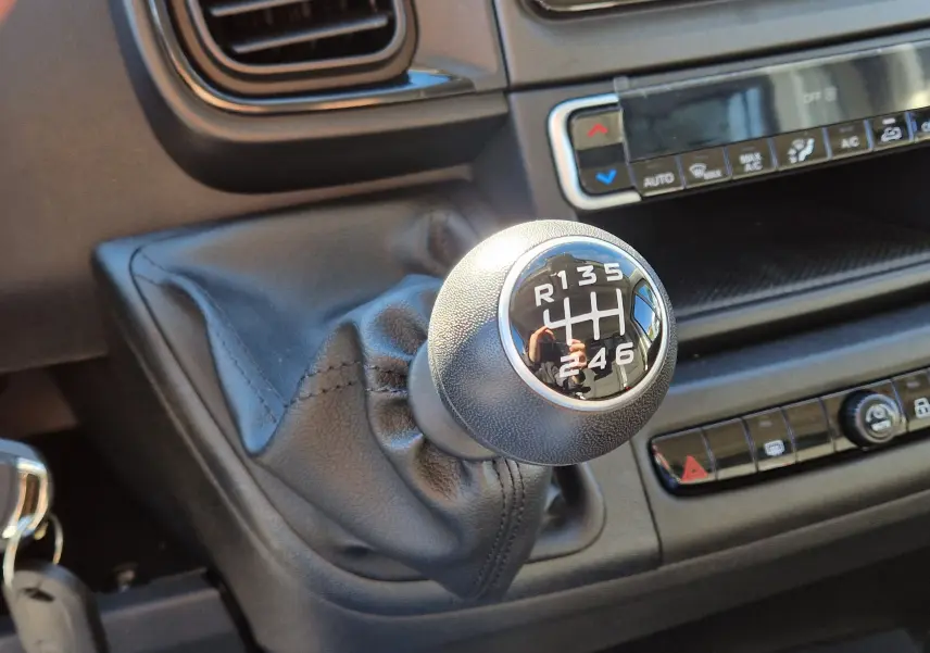 Le levier de vitesse manuel noir du Fiat Ducato Chassis Benne 2023, avec console centrale et commandes climatisation visibles.