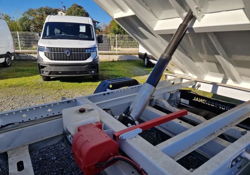 Vue rapprochée du mécanisme de benne relevée d’un FIAT Ducato blanc, avec un fourgon blanc en arrière-plan.