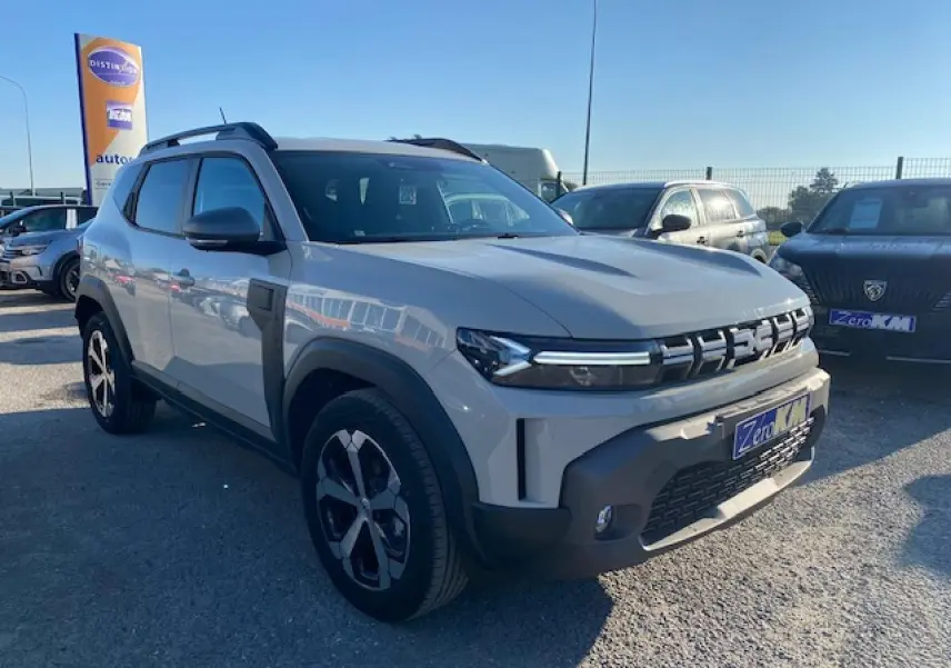 SUV Dacia Duster 2025 beige Sandstone vu en 3/4 avant droit avec calandre distinctive et jantes noires.
