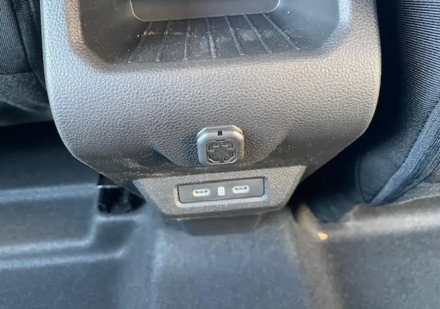 Prise USB double et prise 12V en gros plan au dos de la console centrale du Dacia Duster 2025.