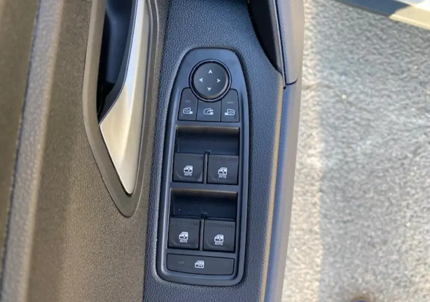 Gros plan sur les commandes des vitres électriques et rétroviseurs sur la portière côté gauche d'un Dacia Duster beige Sandstone 2025.