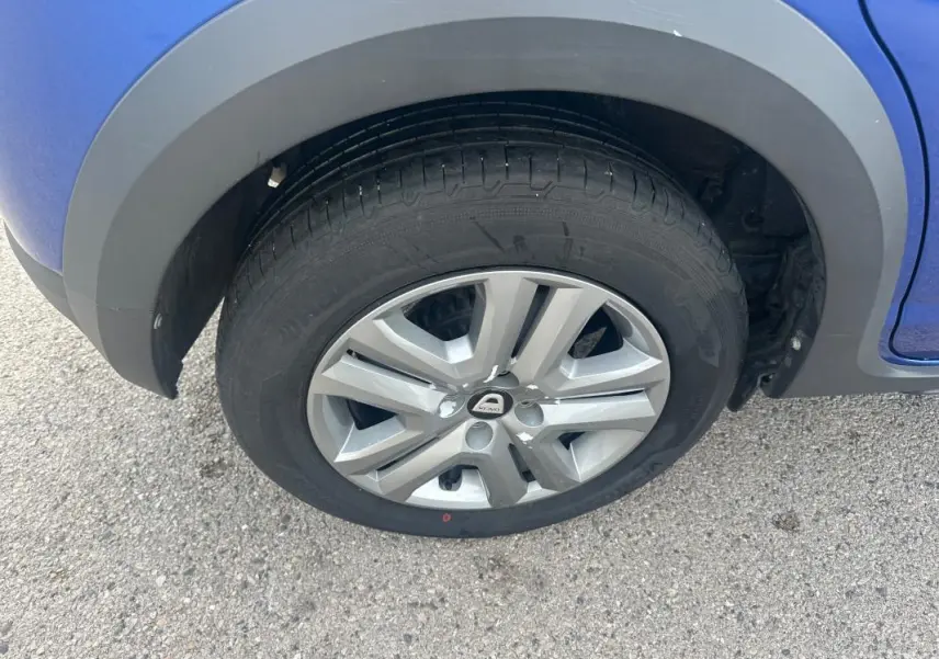 Gros plan sur la roue avant droite d'une Dacia Sandero Stepway bleu foncé avec jante alliage et passage de roue noir.