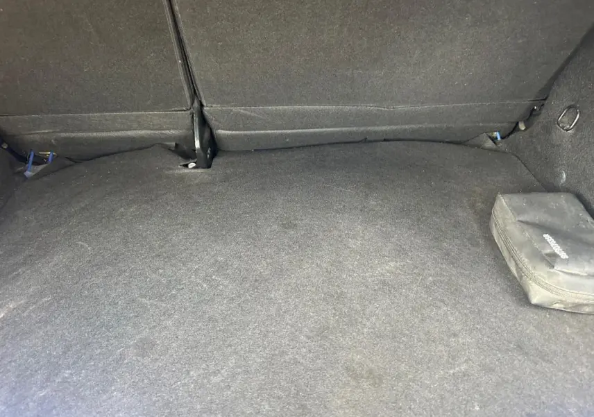 Coffre spacieux de Dacia Sandero Stepway bleu foncé, vue intérieure arrière avec siège rabattable et trousse noire.