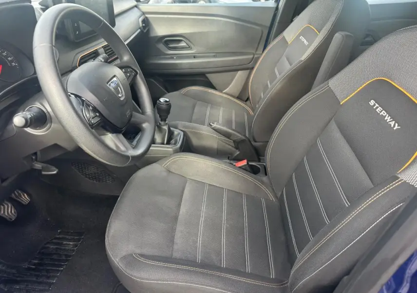 Vue intérieure côté conducteur de la Dacia Sandero Stepway 2021 avec sièges noirs marqués Stepway et volant réglable.