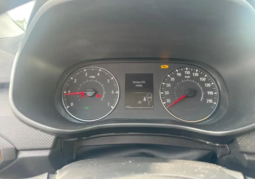 Vue rapprochée du tableau de bord de la Dacia Sandero bleu foncé montrant l'indicateur de niveau GPL faible.