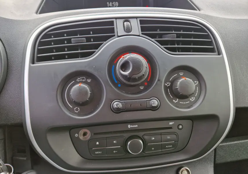 Vue rapprochée du tableau de bord noir du Renault Kangoo 2020, montrant les commandes de climatisation et radio intégrée.
