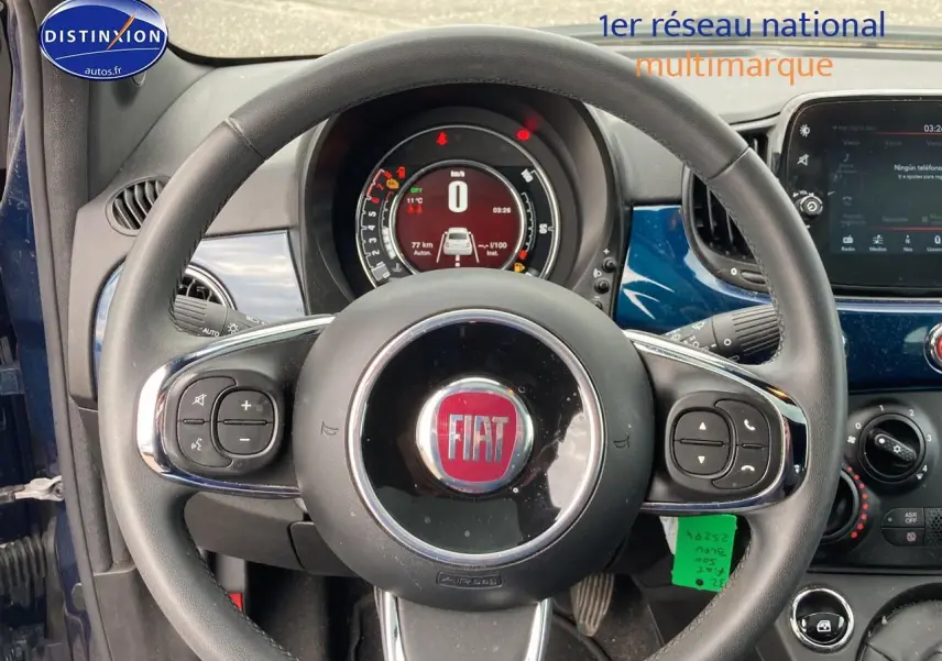 Vue intérieure centrée sur le volant cuir multifonction noir de la Fiat 500 bleu, avec tableau de bord digital en arrière-plan.