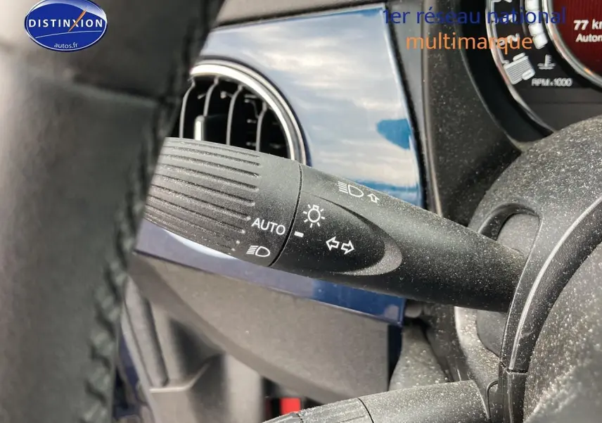 Détail du commodo d’éclairage noir sur fond bleu brillant du tableau de bord d’une FIAT 500 2023.