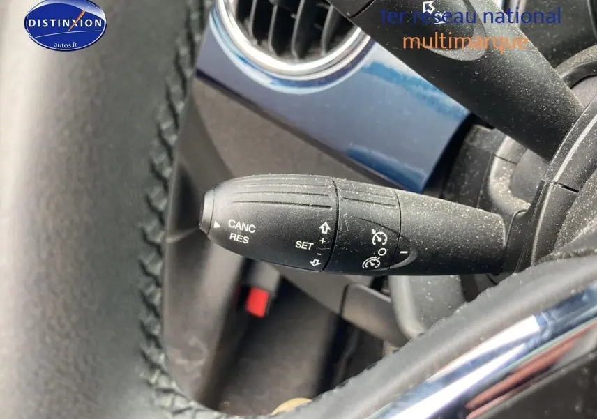 Gros plan sur la commande de régulateur de vitesse côté gauche du volant d’une Fiat 500 bleu 2023.