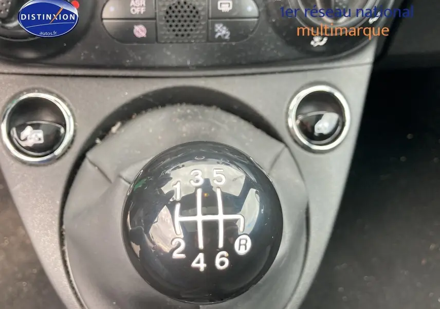 Gros plan sur le levier de vitesses manuel noir de la FIAT 500 bleu, avec console centrale en arrière-plan.