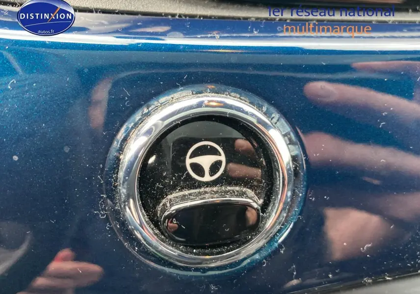 Gros plan sur la poignée de porte chromée d’une FIAT 500 bleue 2023 avec symbole volant gravé.