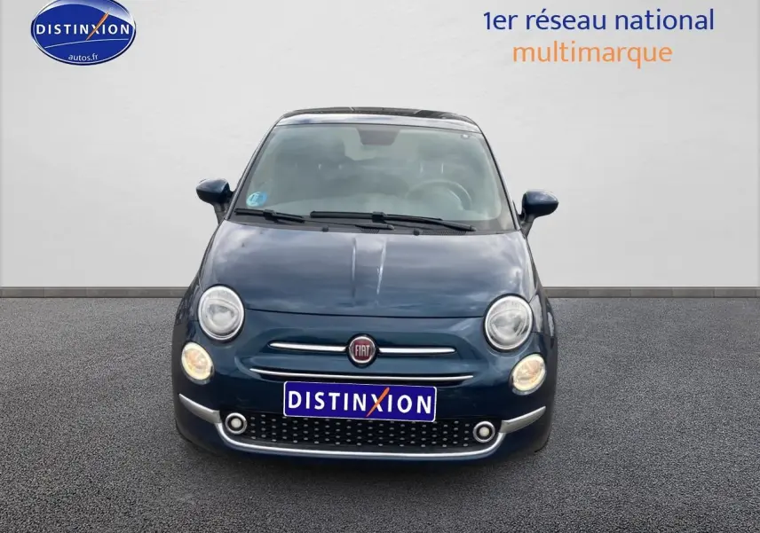 Vue frontale d'une FIAT 500 bleu foncé avec phares allumés et toit panoramique en verre visible.