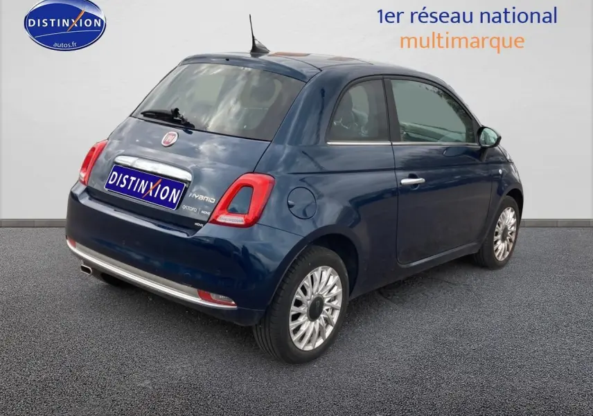 Vue 3/4 arrière droite d'une Fiat 500 bleue 2023 avec jantes alu et toit panoramique en verre.