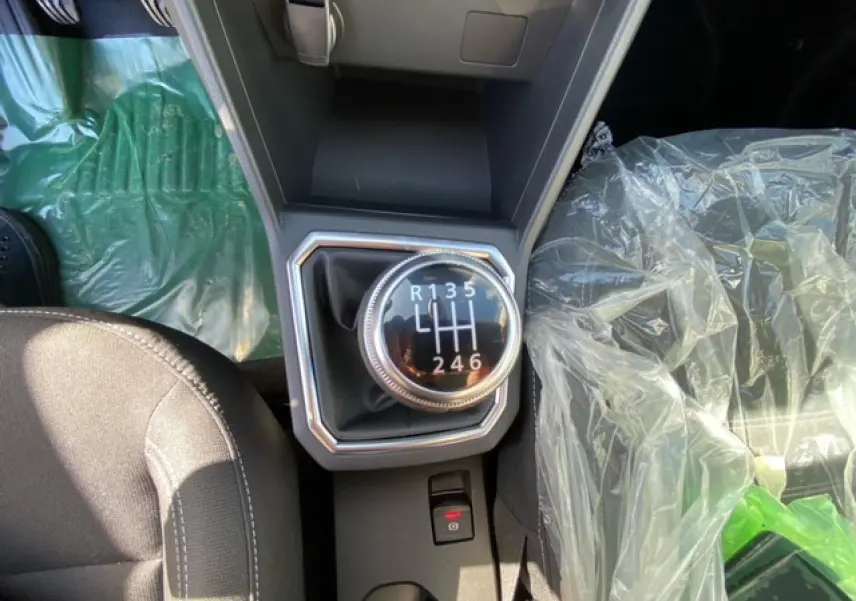 Vue plongeante sur la boîte manuelle de la Dacia Logan gris 2022, avec siège passager protégé par un film plastique.