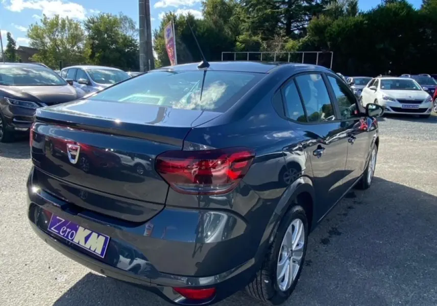 Vue 3/4 arrière droite d'une Dacia Logan gris métallisé 2022 avec feux arrière rouges et antenne de toit.