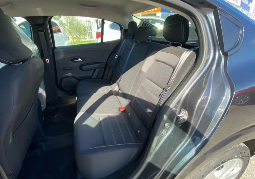 Vue intérieure côté arrière droit de la Dacia Logan gris 2022, montrant les sièges arrière en tissu noir.