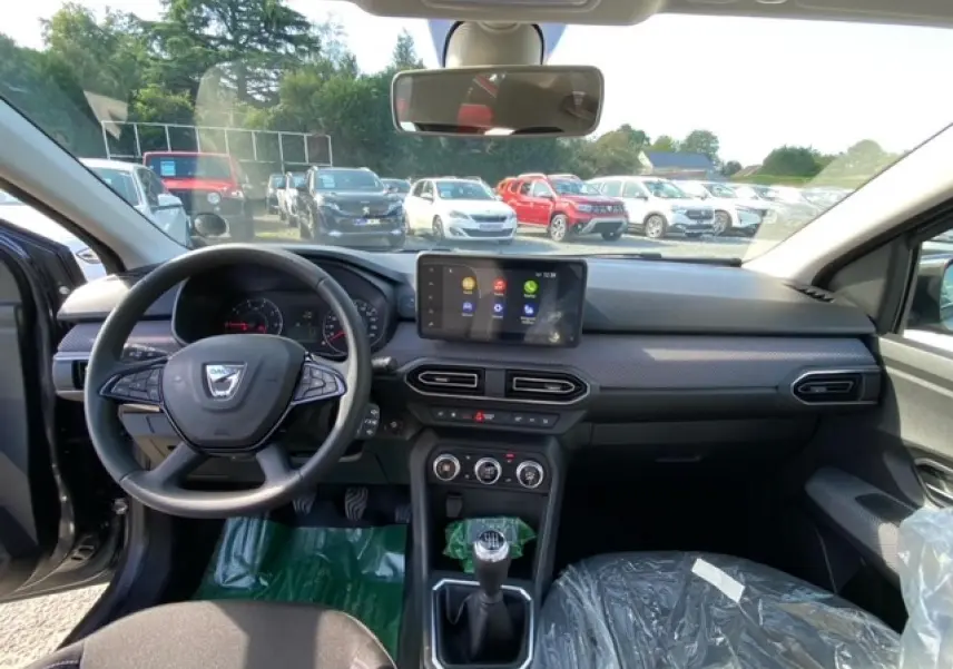 Vue intérieure avant de la Dacia Logan 2022, tableau de bord gris avec écran tactile Media Nav et boîte manuelle.