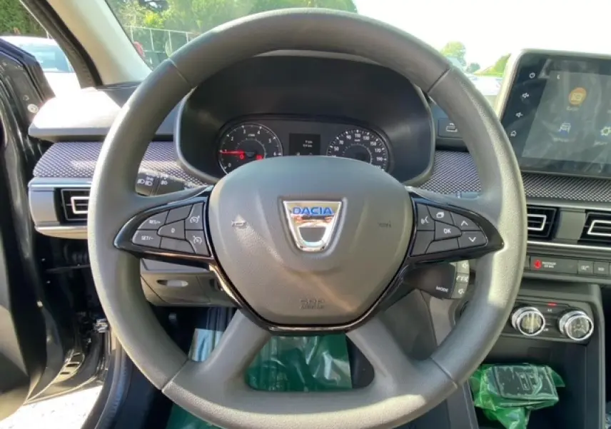 Vue rapprochée du volant gris de la Dacia Logan 2022 avec commandes intégrées et écran tactile Media Nav visible.