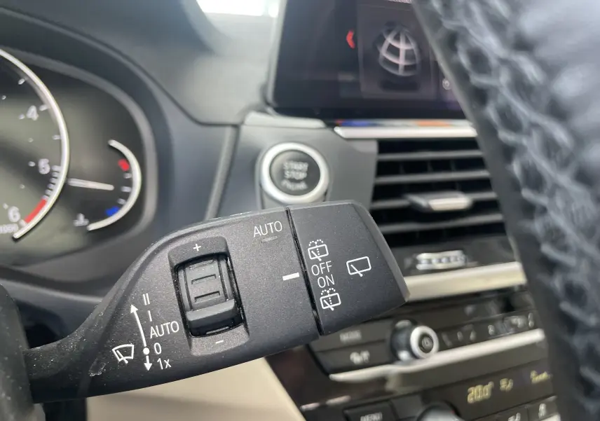 Gros plan sur la commande d’essuie-glace à gauche du volant dans l’habitacle beige d’un BMW X3 noir 2021.