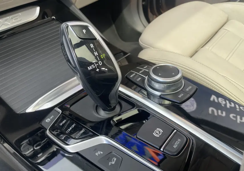 Gros plan sur la console centrale noire du BMW X3 2021, avec levier de vitesse automatique et commandes de mode de conduite.