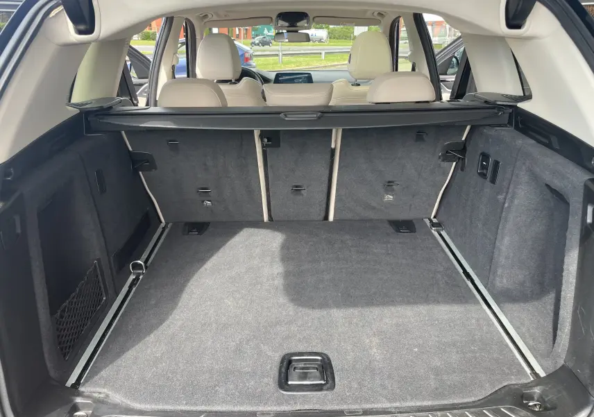 Coffre spacieux vu de l'arrière ouvert d'un BMW X3 noir 2021, avec banquette arrière beige et cache-bagages déployé.