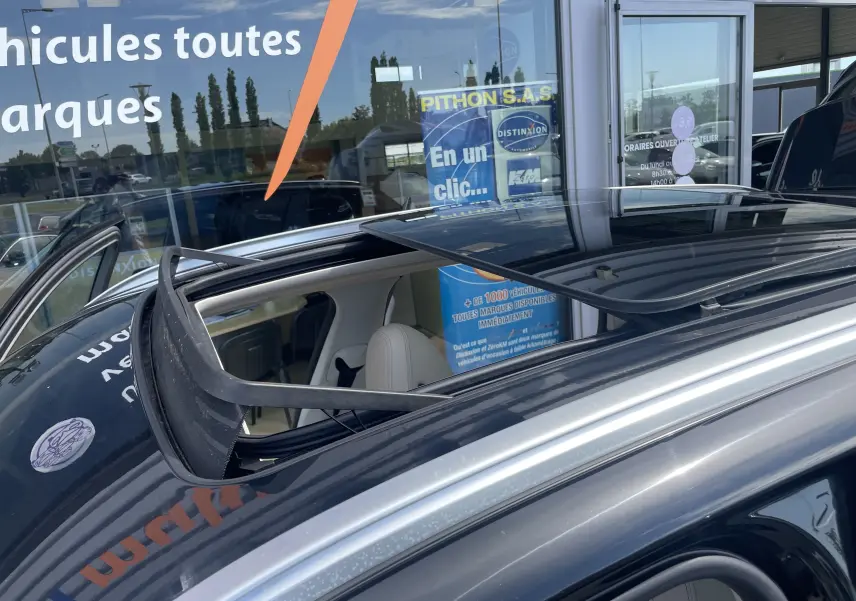 Toit ouvrant panoramique ouvert sur BMW X3 noir, vue rapprochée du toit et intérieur beige visible.