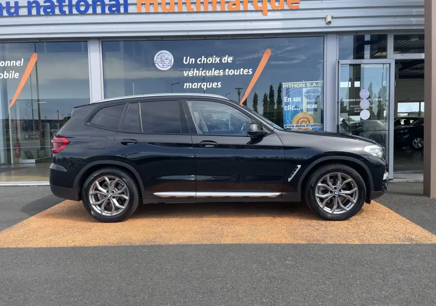 BMW X3 noir vue de profil côté gauche, soulignant ses jantes alliage et ses lignes élégantes sur fond de concession.