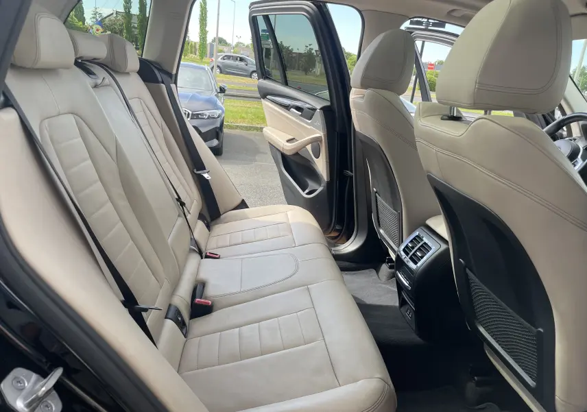 Vue intérieure arrière côté gauche d'un BMW X3 noir 2021, montrant les sièges en cuir beige et la portière ouverte.