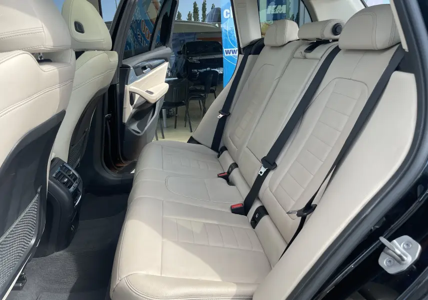 Vue intérieure arrière côté droit du BMW X3 noir 2021, sièges en cuir beige avec ceintures de sécurité visibles.