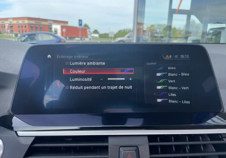 Écran central intérieur de BMW X3 G01 noir 2021 montrant le menu de réglage de la lumière d'ambiance avec choix de couleur lilas.