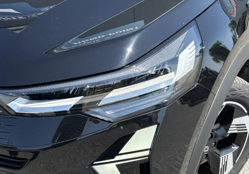 Gros plan sur le phare avant droit et la jante 18" du Renault Symbioz noir étoilé, soulignant les détails LED Pure Vision.