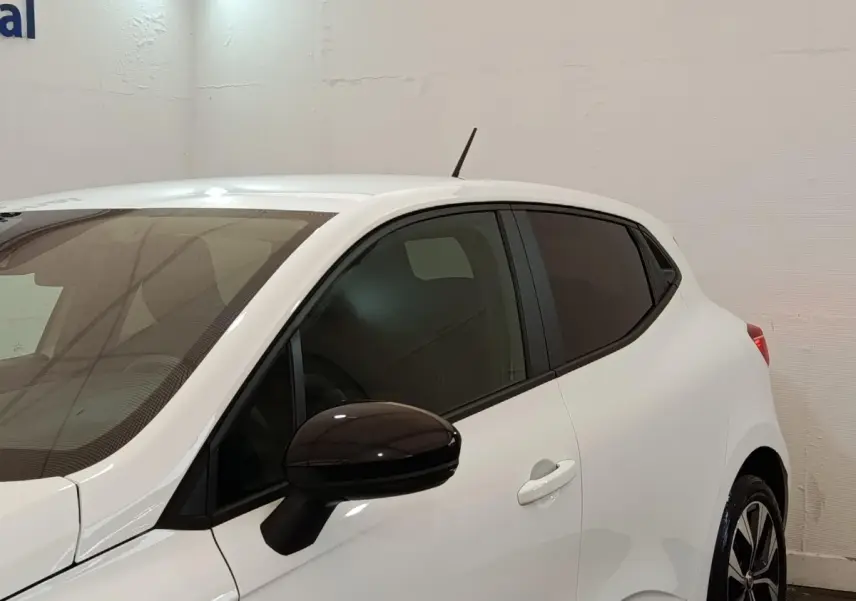 Vue latérale droite d'une Renault Clio Evolution TCe 90 blanche avec rétroviseur noir et vitres teintées.