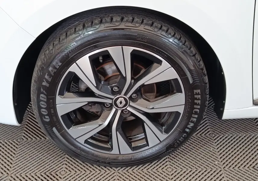 Gros plan sur la roue avant droite d'une Renault Clio blanche avec jante alliage bicolore et logo central Renault.