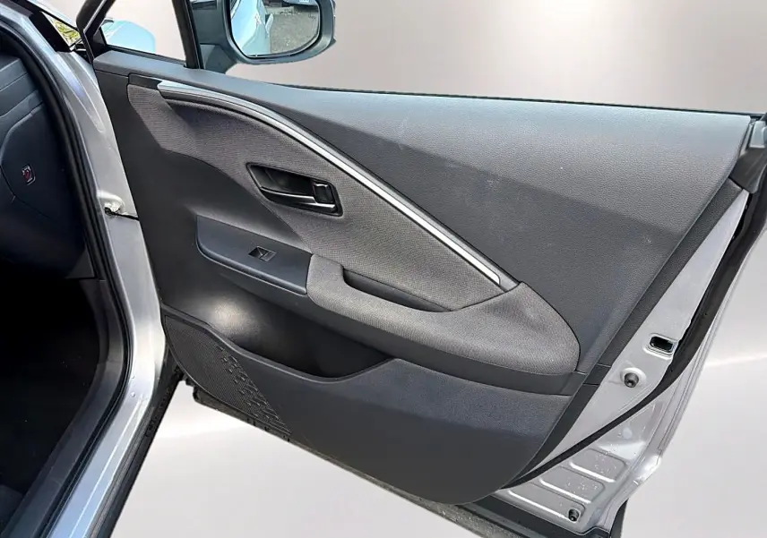 Vue intérieure de la porte avant gauche gris foncé du Toyota C-HR 1.8 hybride 2025 avec poignée et commande de vitre.