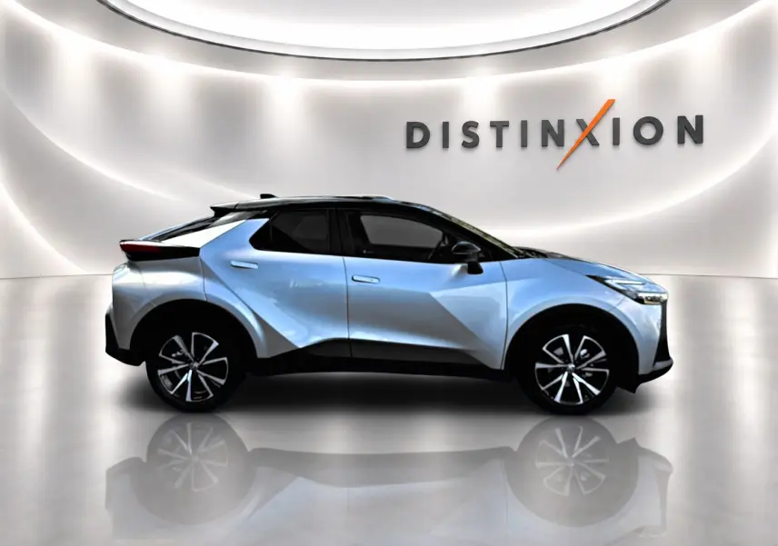 Vue de profil côté gauche du Toyota C-HR 1.8 hybride gris clair avec toit noir dans un showroom lumineux.
