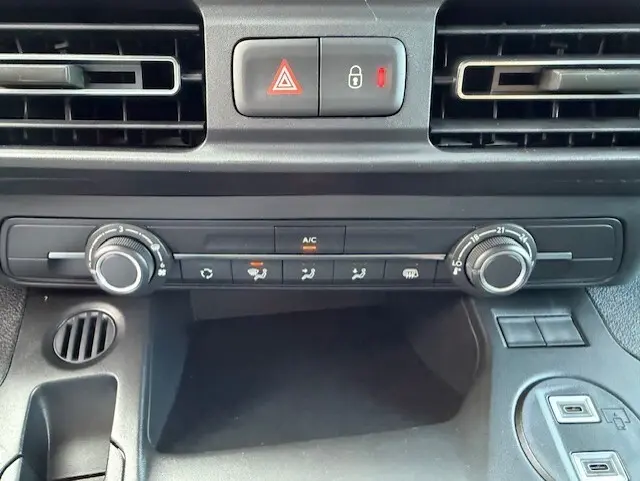Vue rapprochée du tableau de bord du Citroën Berlingo blanc 2026, montrant les commandes de climatisation et les aérateurs.